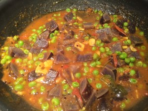 Tomato-garlic gravy with purple potatoes and peas